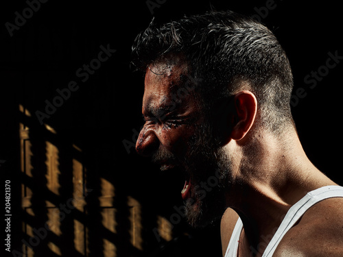 Portrait of a strong man with a beard, face in blood. He looks at the camera with different emotions. Blood and sweat dripping down his face. Fists erased from strikes
