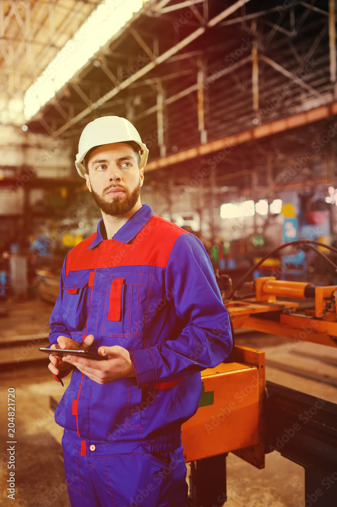 Portrait of a beautiful engineer in a construction helmet with a touch tablet on a factory background Portrait of a beautiful engineer in a construction helmet with a touch tablet on a factory background