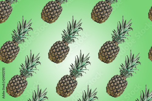 Pattern with pineapples on pastel background. Colorful fruit pattern of fresh pineapples on green background. Top view on pineapples.