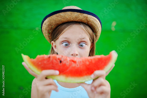 baby girl greedily eating ripe watermelon on a green background