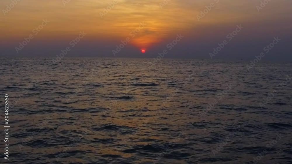 Tropical sunset. Red sun sets over the ocean, the sea waves in the evening light, beautiful afterlight Tropical sunset. Red sun sets over the ocean, the sea waves in the evening light, beautiful afterlight