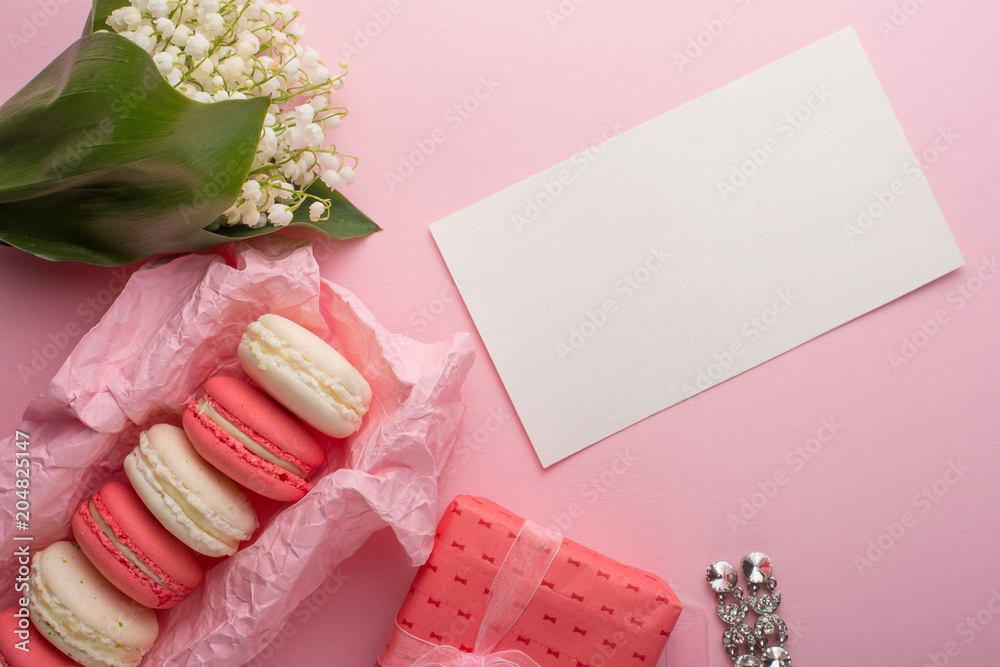 Flatlay with macaroons, flowers and a gift with female earrings and an empty place for inscription on a light pink background. Can be used as a postcard for a holiday Flatlay with macaroons, flowers and a gift with female earrings and an empty place for inscription on a light pink background. Can be used as a postcard for a holiday