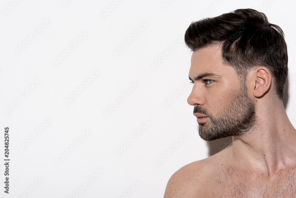 Profile of attractive bearded naked guy is standing and looking aside wistfully. Copy space in the left side. Beauty concept Profile of attractive bearded naked guy is standing and looking aside wistfully. Copy space in the left side. Beauty concept