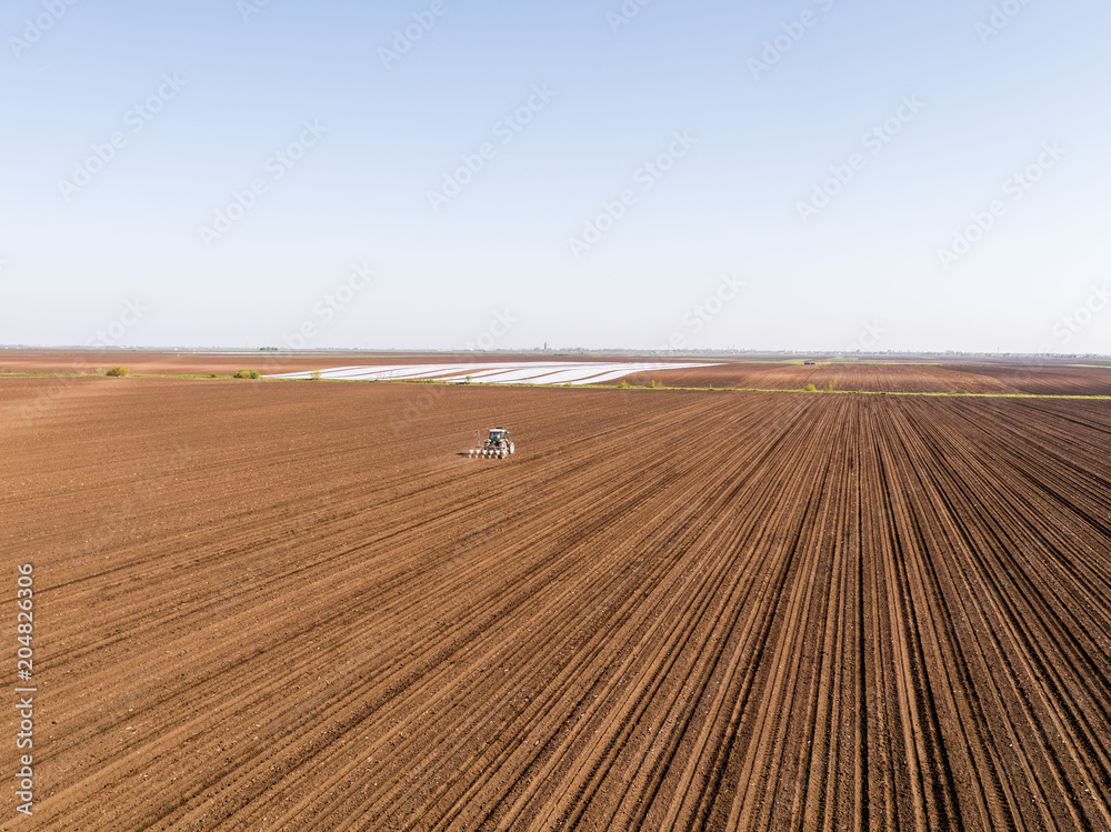 Aerial shot of a farmer seeding, sowing crops at field. Sowing is the process of planting seeds in the ground as part of the early spring time agricultural activities. Aerial shot of a farmer seeding, sowing crops at field. Sowing is the process of planting seeds in the ground as part of the early spring time agricultural activities.