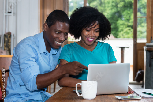 Laughing african american love couple indoors at computer