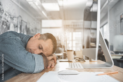 Portrait of calm tired male sleeping on table during job in office