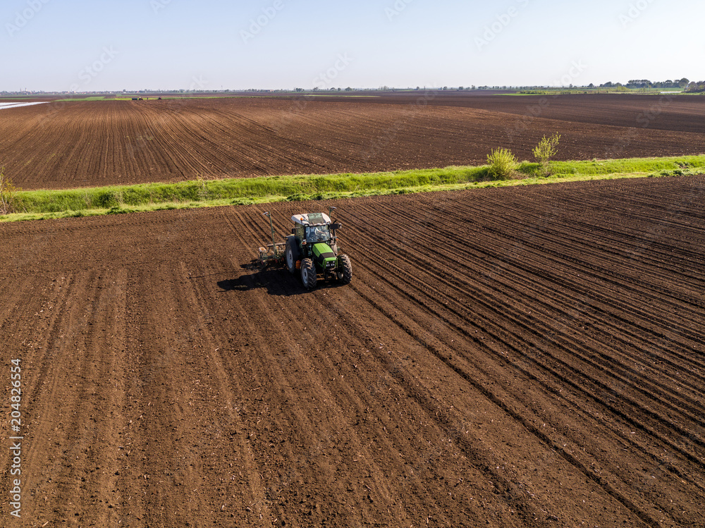 Aerial shot of a farmer seeding, sowing crops at field. Sowing is the process of planting seeds in the ground as part of the early spring time agricultural activities. Aerial shot of a farmer seeding, sowing crops at field. Sowing is the process of planting seeds in the ground as part of the early spring time agricultural activities.