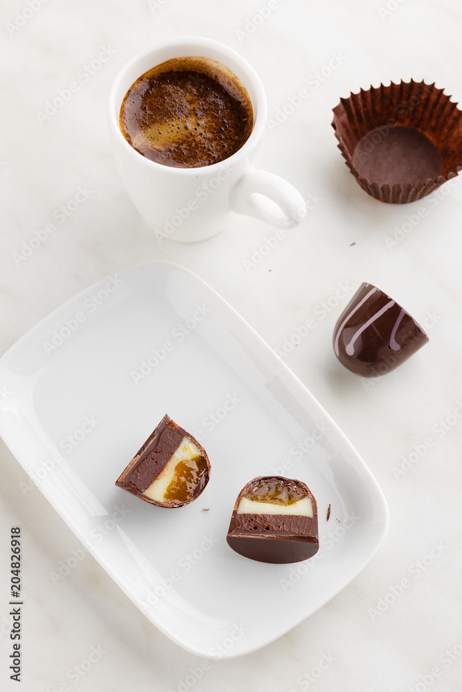 Top view of cut handmade bonbon with ganache and fruit confiture filling on plate with cup of coffee Top view of cut handmade bonbon with ganache and fruit confiture filling on plate with cup of coffee