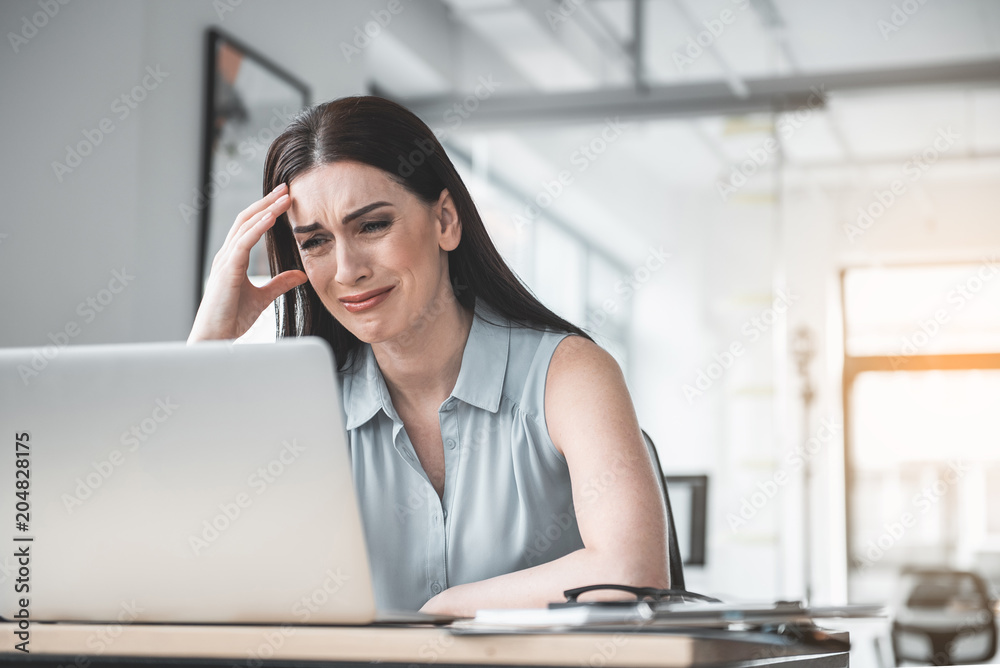 Portrait of crying girl watching at digital device while having job in office. Big trouble during labor concept Portrait of crying girl watching at digital device while having job in office. Big trouble during labor concept