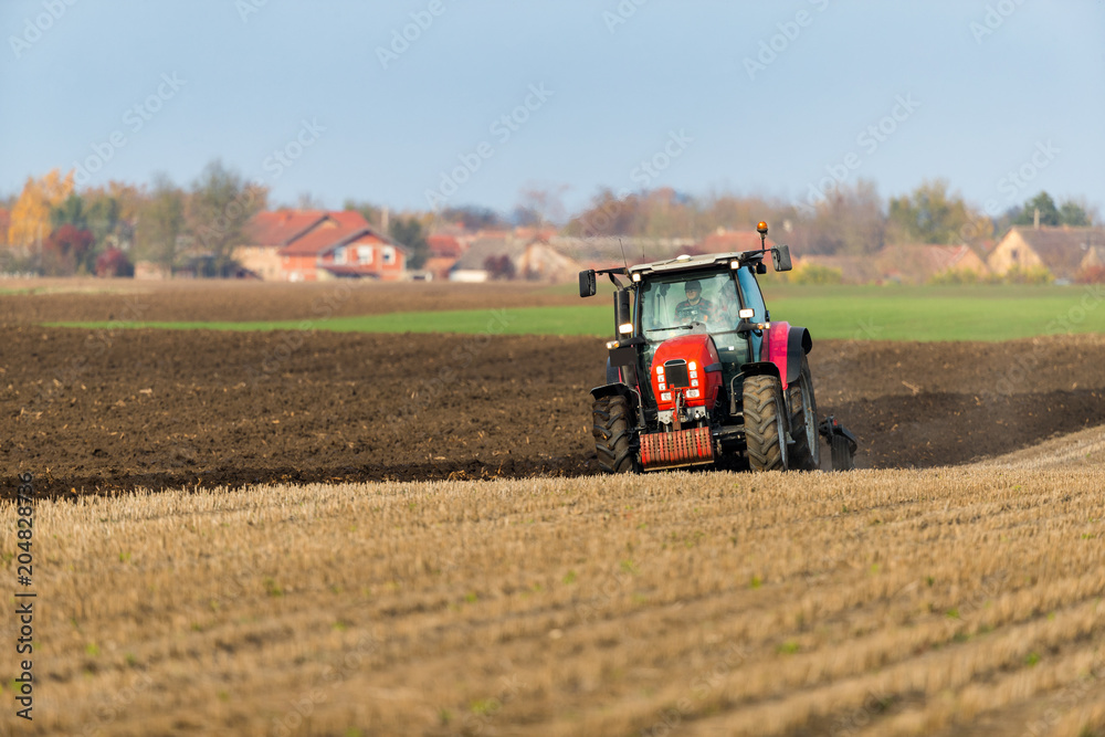 Fototapeta premium Farmer plowing stubble field