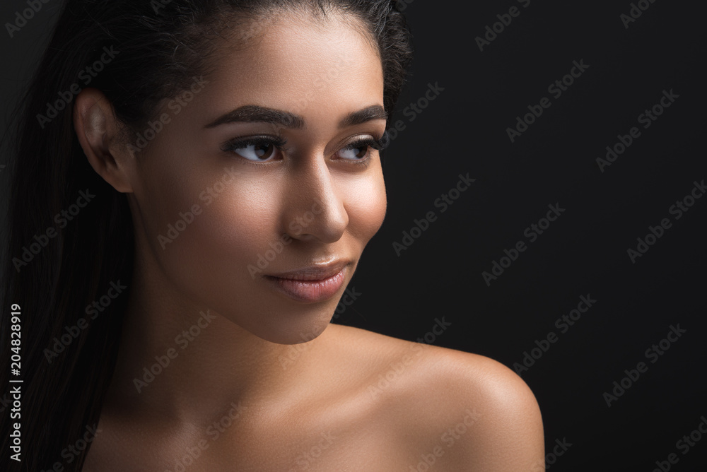 Fototapeta premium Portrait of thoughtful female person having perfect facial and body skin. Copy space in right side. Isolated on black background