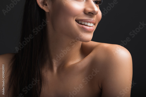 Close up of happy girl with long hair, soft skin and beautiful smile. Isolated on black background