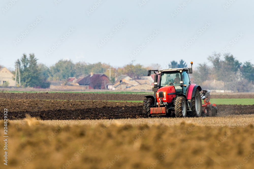 Obraz premium Farmer plowing stubble field