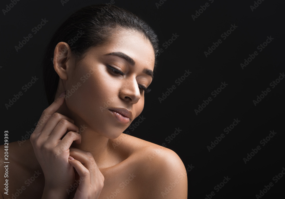 Portrait of tranquil nice woman touching her pelt after cosmetology procedure. Copy space in right side. Isolated on black background Portrait of tranquil nice woman touching her pelt after cosmetology procedure. Copy space in right side. Isolated on black background