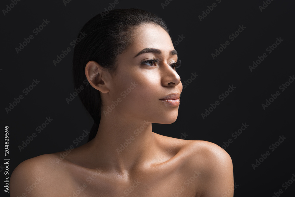 Well groomed female face with pensive look. Her shoulders are undressed. Isolated on black background Well groomed female face with pensive look. Her shoulders are undressed. Isolated on black background