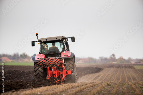 Farmer plowing stubble field photo