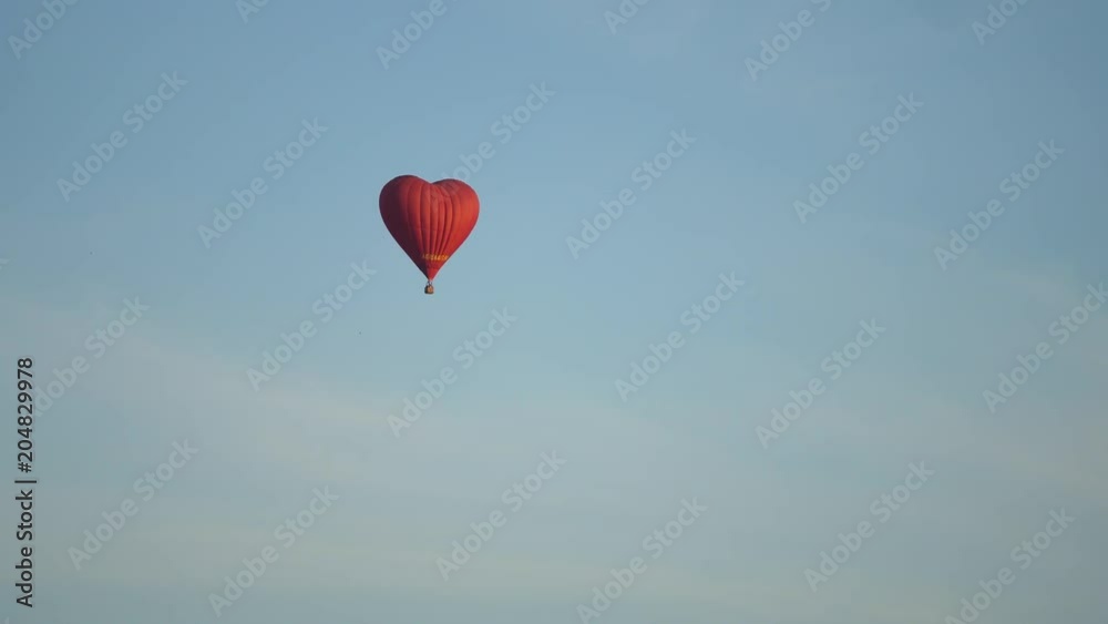 Hot air balloon shape of a heart in the blue sky. Aerostat, Airship. Red balloon.4k Hot air balloon shape of a heart in the blue sky. Aerostat, Airship. Red balloon.4k