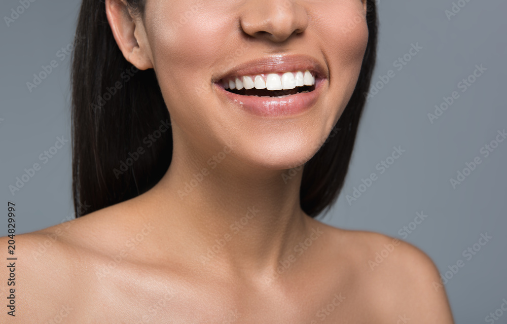 Close up of female lower face and bare body. She is showing snow white perfect teeth. Isolated on background Close up of female lower face and bare body. She is showing snow white perfect teeth. Isolated on background