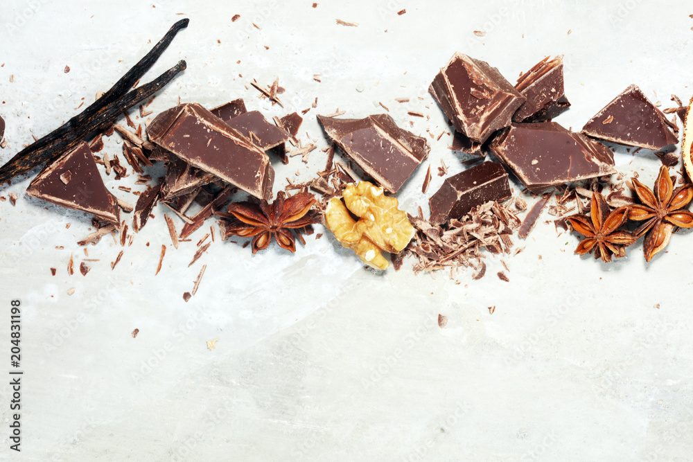 Fototapeta premium dark chocolate bars with anise and nutson stone table and broken pieces of cocoa