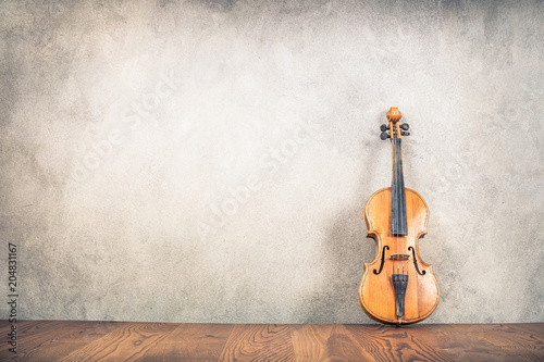 Fototapeta Vintage antique violin near old textured concrete wall background. Retro style filtered photo