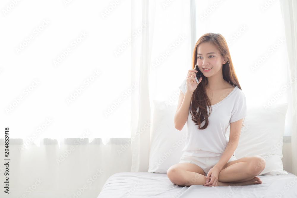 Beautiful of portrait young asian woman talking smart mobile phone and smile sitting at curtain background on bedroom, girl calling telephone, communication concept. Beautiful of portrait young asian woman talking smart mobile phone and smile sitting at curtain background on bedroom, girl calling telephone, communication concept.