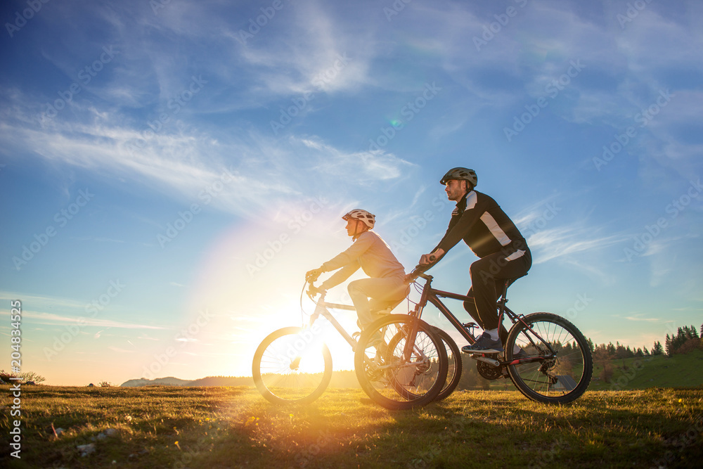 Happy mountainbike couple outdoors have fun together on a summer afternoon sunset