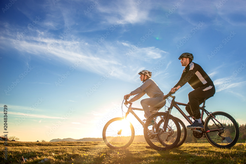 Happy mountainbike couple outdoors have fun together on a summer afternoon sunset Happy mountainbike couple outdoors have fun together on a summer afternoon sunset
