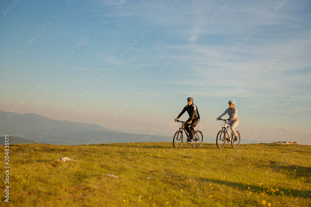 Happy mountainbike couple outdoors have fun together on a summer afternoon sunset