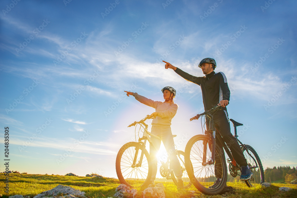 Biker couple with mountain bike pointing in distance at countryside Biker couple with mountain bike pointing in distance at countryside