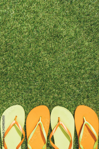 top view of green and orange flip flops on green lawn