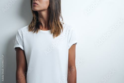 woman in white blank t-shirt, empty wall, horizontal studio close-up