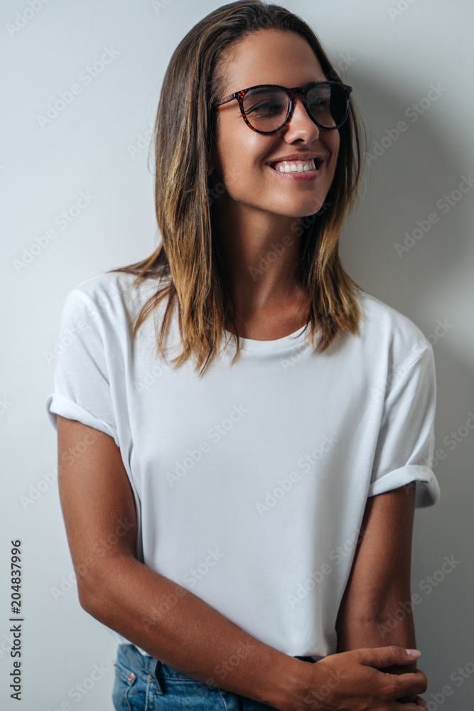 Pretty woman in white blank t-shirt wearing glasses, empty wall, verticalstudio portrait Pretty woman in white blank t-shirt wearing glasses, empty wall, verticalstudio portrait