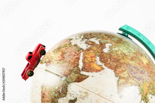 close-up shot of red toy car riding on globe isolated on white