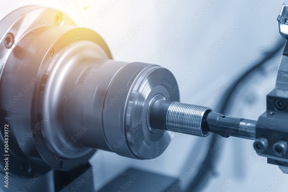 The CNC lathe machine or turning machine cutting the thread at the end of metal pipe or tube. Modern manufacturing process. The CNC lathe machine or turning machine cutting the thread at the end of metal pipe or tube. Modern manufacturing process.