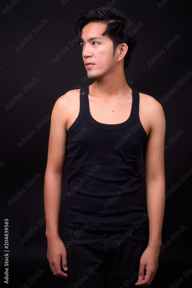 Young handsome Asian man against black background Young handsome Asian man against black background