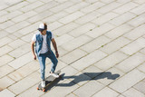 high angle view of handsome young skater riding skateboard by square