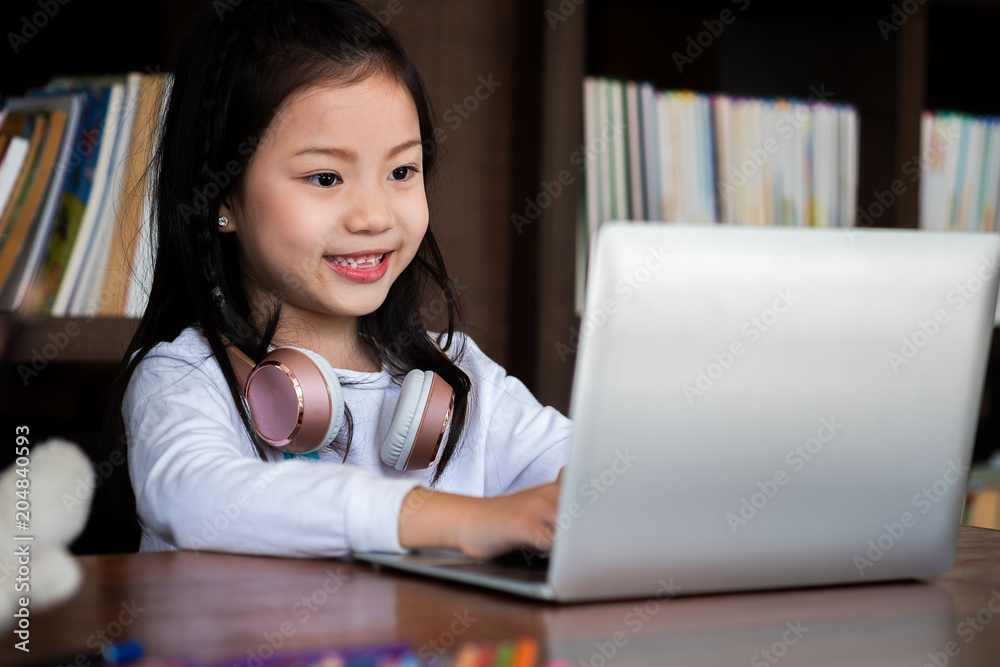 cute girl smile sitdown and playing laptop computer in the library, children concept, education concept cute girl smile sitdown and playing laptop computer in the library, children concept, education concept