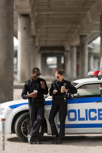 Bild auf Leinwand police officers with coffee and doughnuts standing next to car
