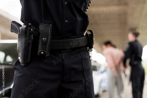 cropped image of policeman belt with gun and handcuffs