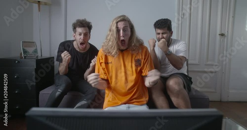 Cheerful Holland football supporters celebrating goal while watching football match on television at home