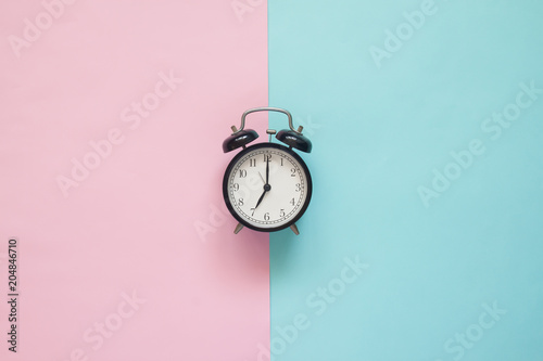 Flat lay clock on pink and blue background, Pastel colors concept
