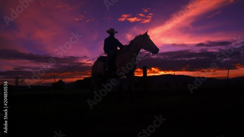 a cowboy on a horse silhouetted against sky as the sun sets.