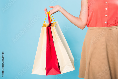 Close up of woman with colored shopping bags over blue background