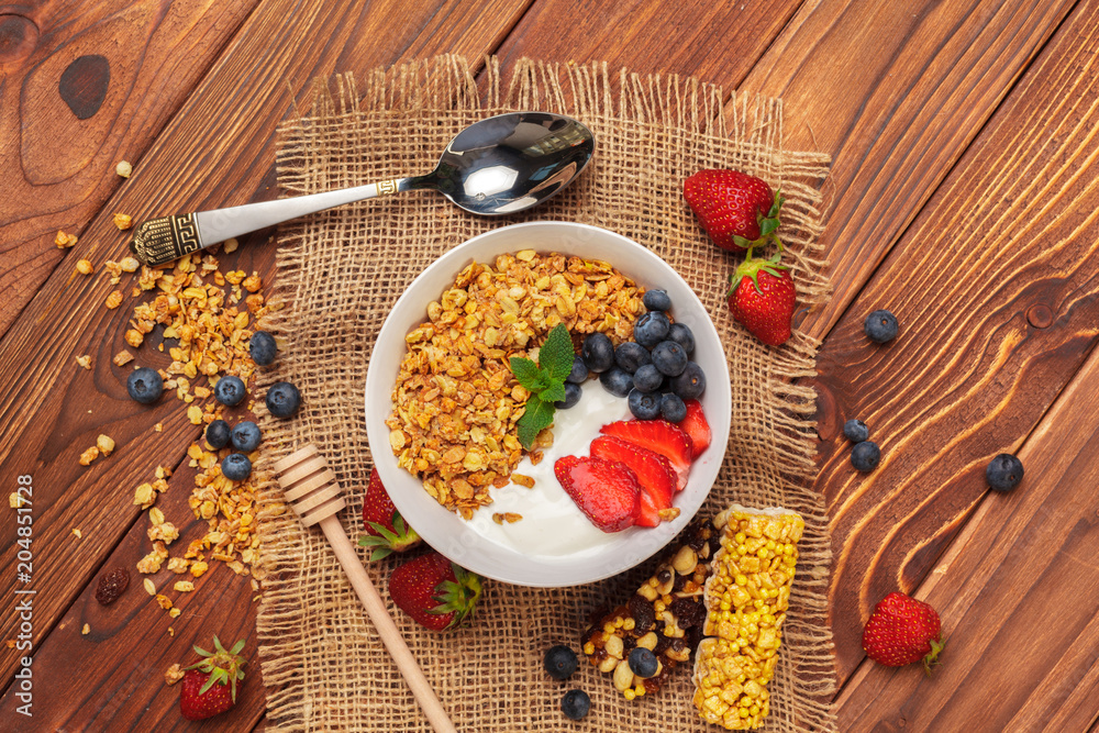 Bowl of homemade granola with yogurt and fresh berries on wooden background Bowl of homemade granola with yogurt and fresh berries on wooden background