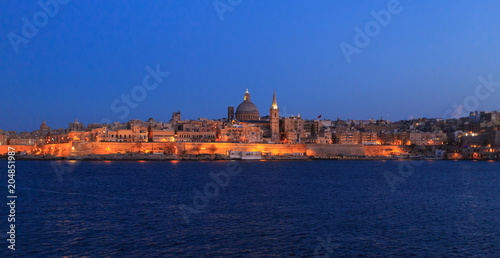 Valletta, Malta in the evening. Panoramic view of illuminated historic island and the dome of Carmelite Church and St Paul`s tower.