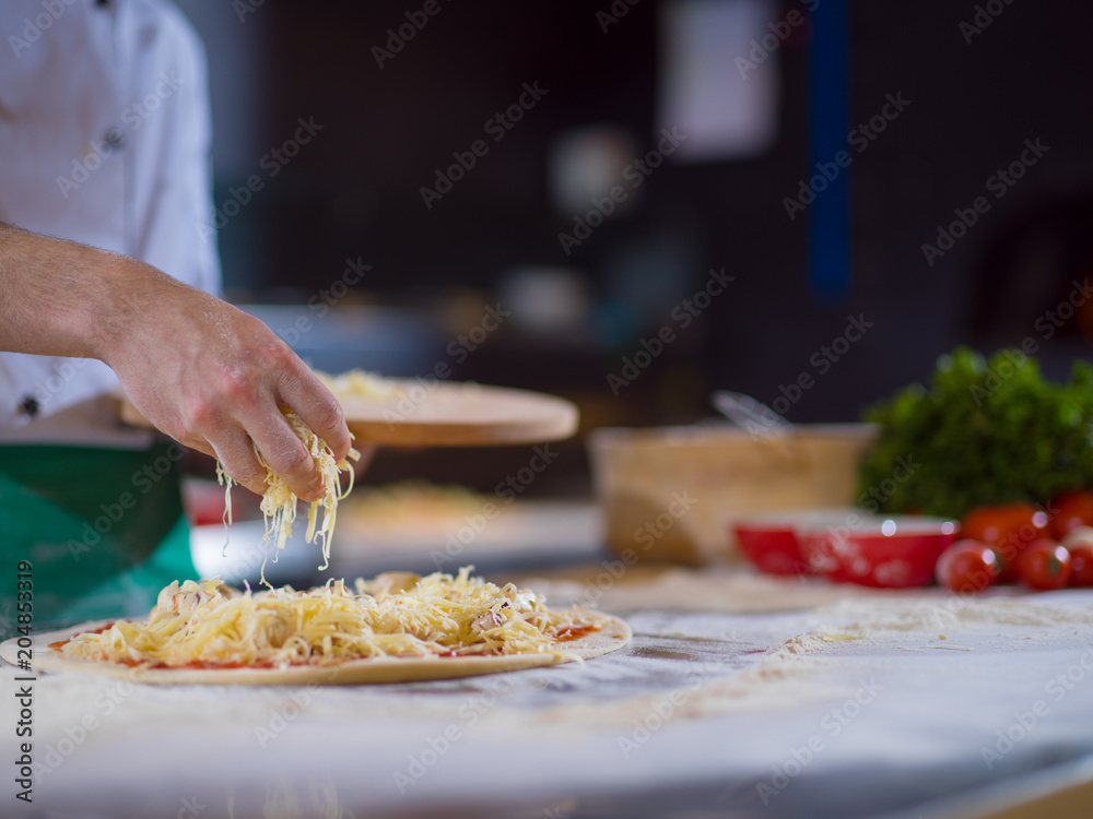 chef sprinkling cheese over fresh pizza dough