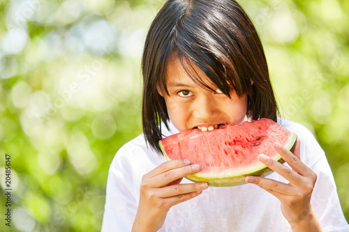 Asiatisches Mädchen beißt in eine Wassermelone
