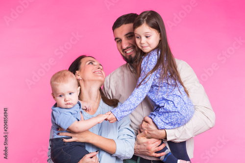 Portrait of Young Happy Mixed Race Family over pink background.