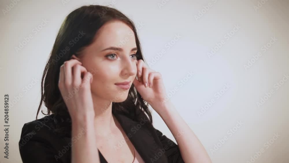 Girl puts on wireless headphones, white background.
Girl puts on wireless headphones, white background.
