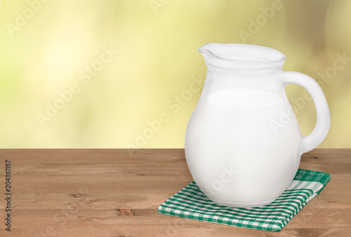 Jug of milk and on napkin on wooden table